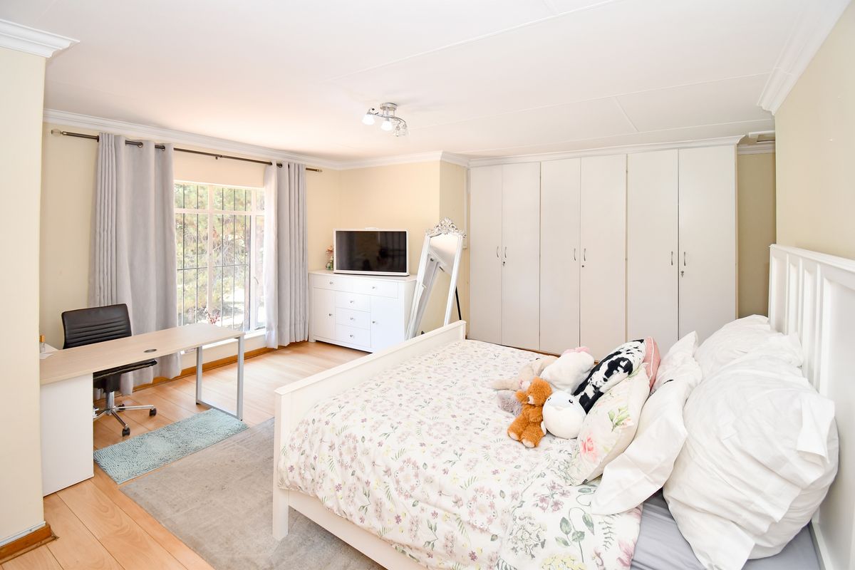 Spacious bedroom featuring extensive built-in cupboards, laminate flooring, and large windows allowing for natural light.