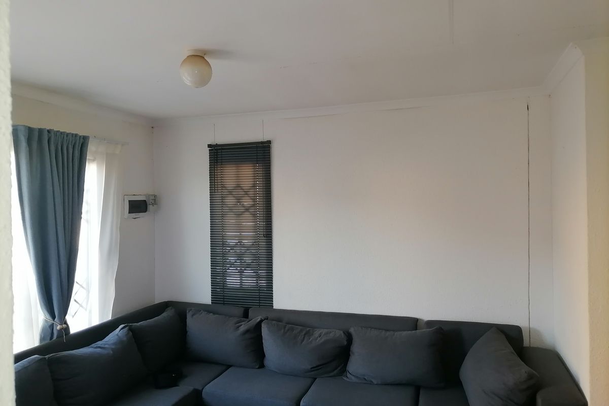 A living room featuring a window with fitted blinds and a ceiling-mounted light fixture.
