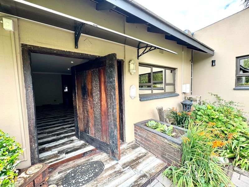 Front entrance area featuring a rustic timber door, brick planter box, and a protective metal awning over a tiled patio.