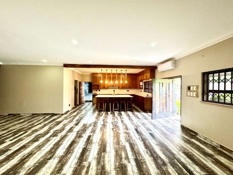 Spacious open-plan living area featuring a modern kitchen with a central island, wooden cabinetry, and distinctive wood-look tiled flooring throughout.