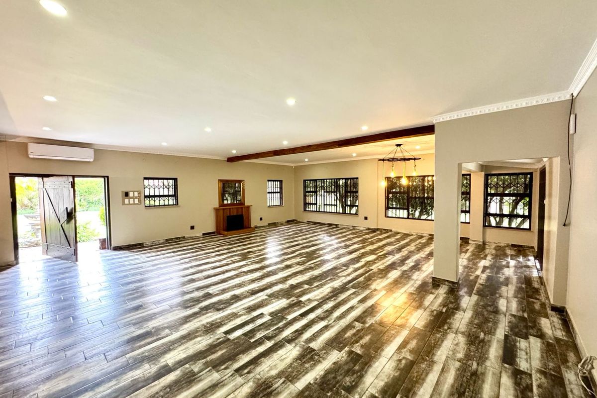 Spacious open-plan living area featuring wood-look tile flooring, a fireplace, recessed lighting, and large windows with security bars.
