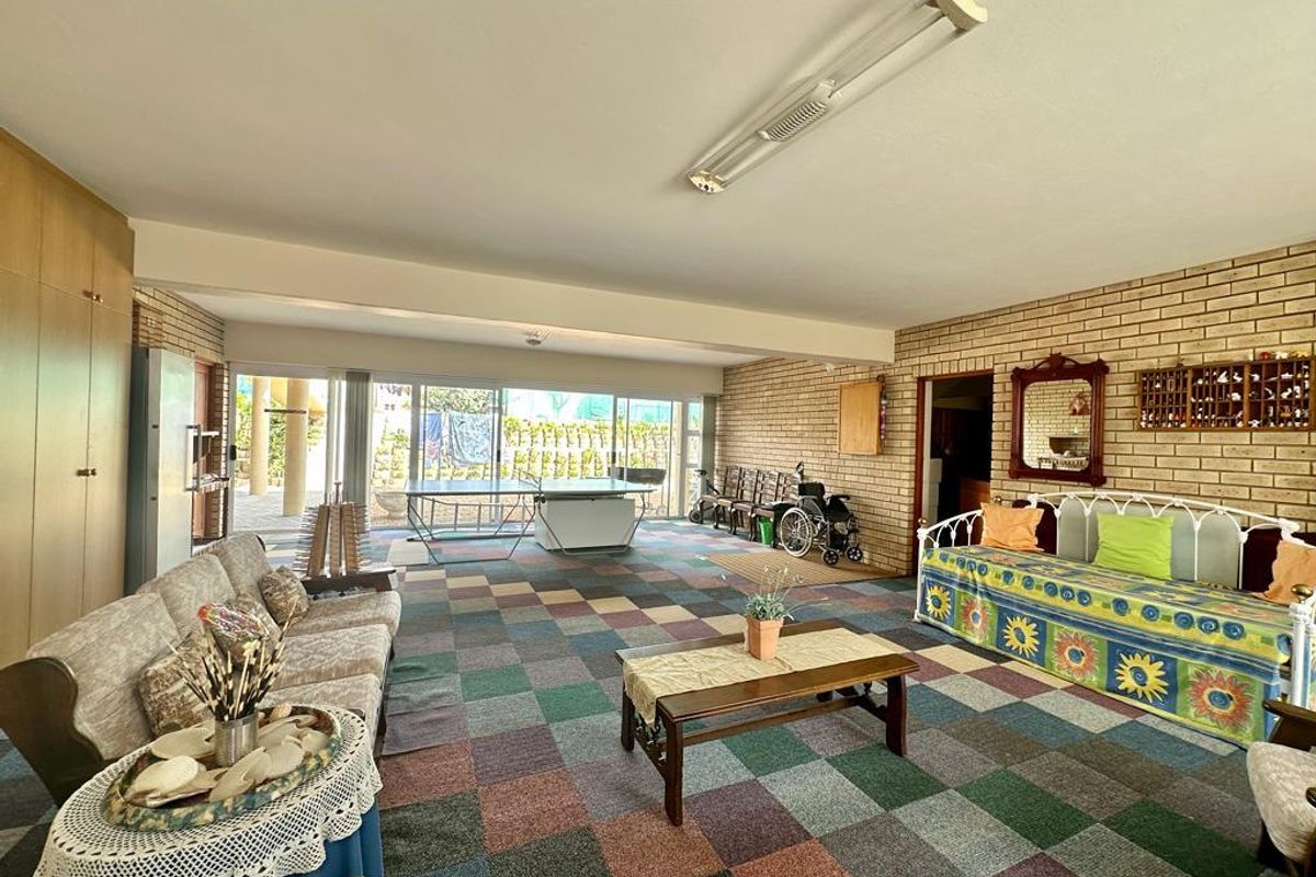 Spacious living area featuring exposed brick walls, large sliding glass doors leading to the patio, and multi-colored carpet tiles.