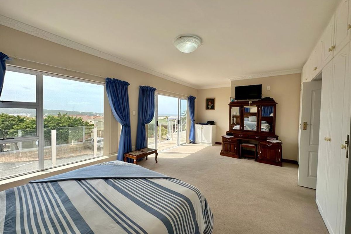 Spacious bedroom featuring large windows with scenic views, built-in wardrobes, and direct access to an outdoor balcony area.
