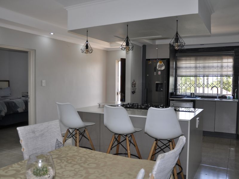 Modern open-plan kitchen featuring a central island with a built-in hob, sleek cabinetry, and contemporary pendant lighting, seamlessly flowing into the dining area.