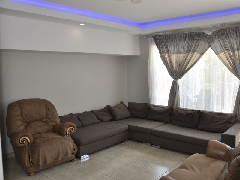 A living room featuring tiled flooring and a recessed ceiling with integrated blue LED accent lighting.