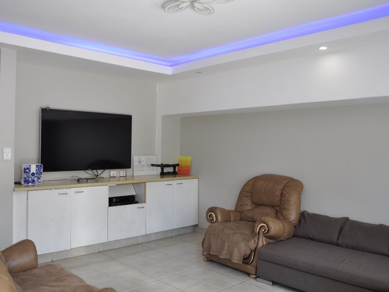 Living room featuring built-in cabinetry, tiled flooring, and modern recessed ceiling lighting with integrated ambient LED strips.