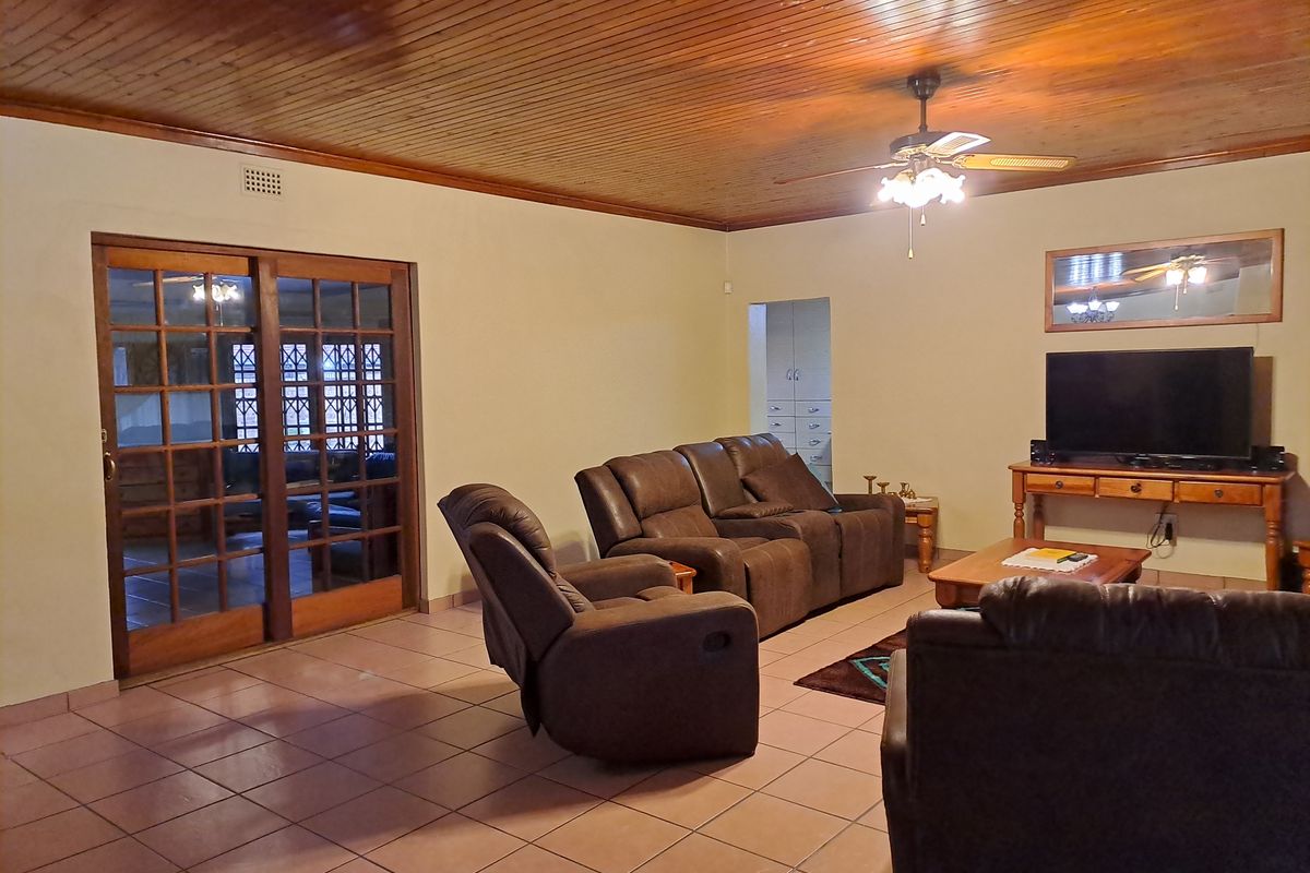Spacious living room featuring a timber-paneled ceiling, tiled flooring, and a large wooden sliding door leading to an adjacent room.