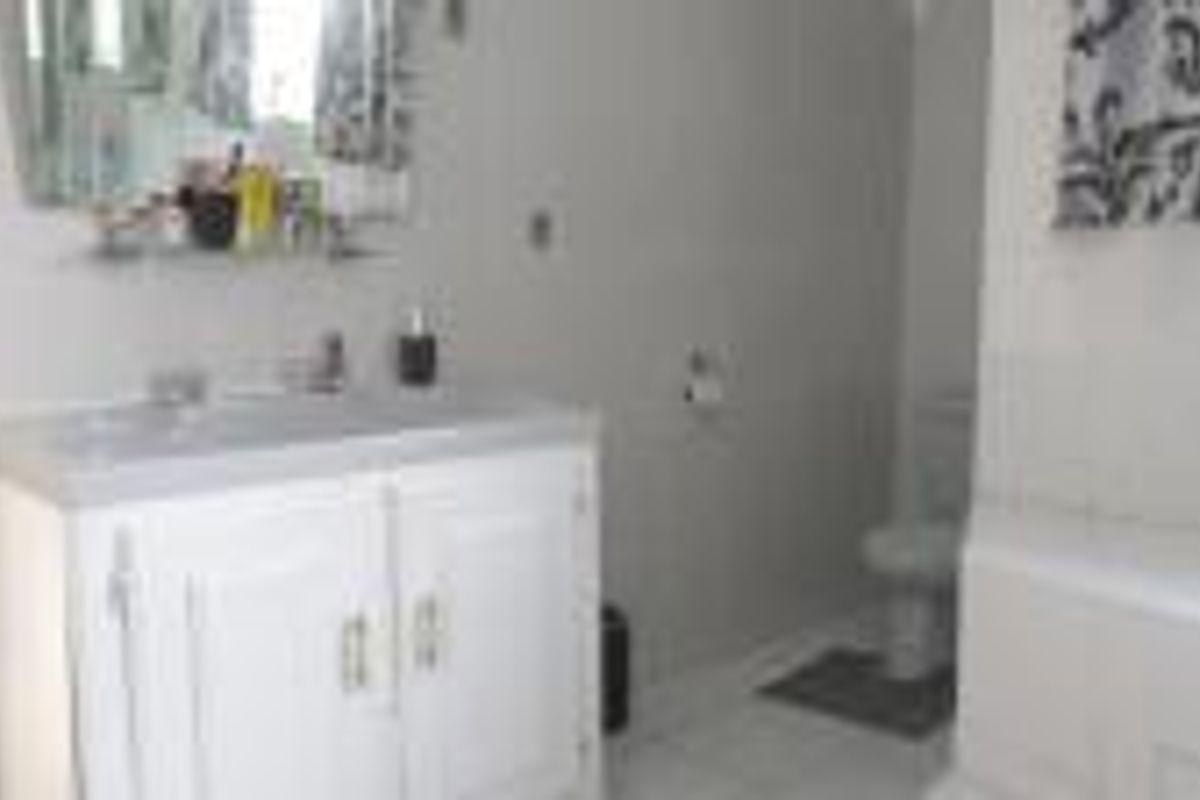 A functional bathroom featuring a white vanity cabinet with basin, a standard toilet, and a bathtub with tiled flooring.