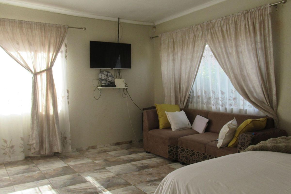 A living room area featuring tiled flooring and dual windows with installed curtain rods.