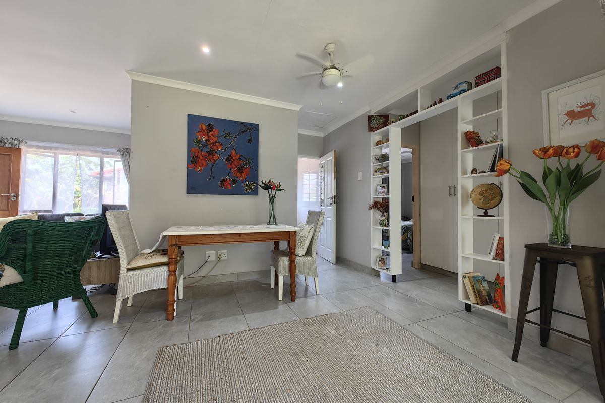 A bright living area featuring tiled flooring, recessed lighting, a ceiling fan, and a functional built-in shelving unit providing integrated storage.
