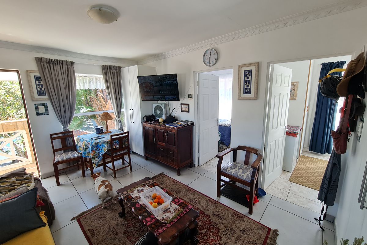 A living room area featuring tiled flooring, decorative ceiling cornices, and access to an outdoor patio through a sliding glass door.