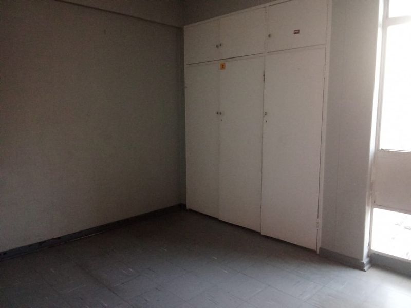 An empty bedroom featuring built-in cupboards and tiled flooring, offering a blank canvas for renovation or interior design updates.