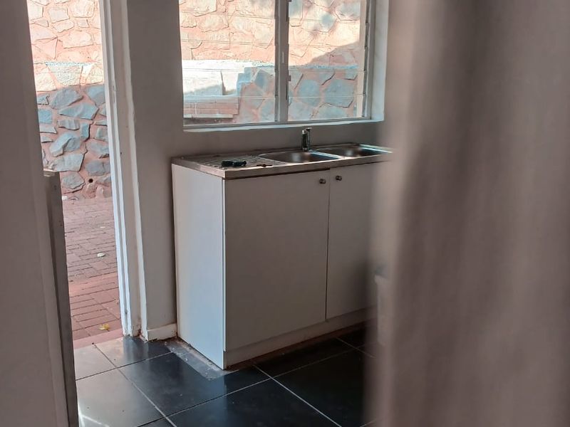 A functional scullery or utility area featuring built-in cabinetry, a stainless steel sink, and direct access to the outdoor patio area.