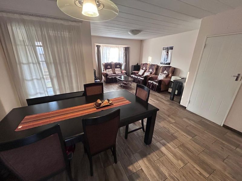 An open-plan living and dining area featuring tiled flooring, a panelled ceiling, and a sliding glass door providing access to the exterior.