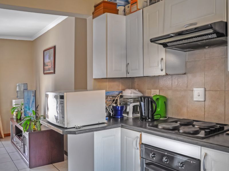 Open-plan kitchen area featuring white cabinetry, dark countertops, and integrated cooking appliances, flowing into the adjacent living space.