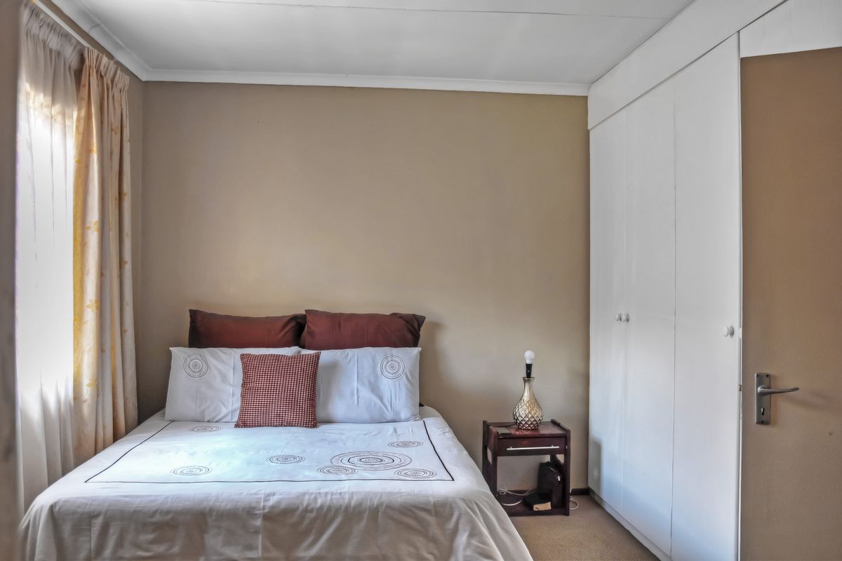 A functional bedroom featuring built-in cupboards and carpeted flooring, providing a neutral space ready for personalization.