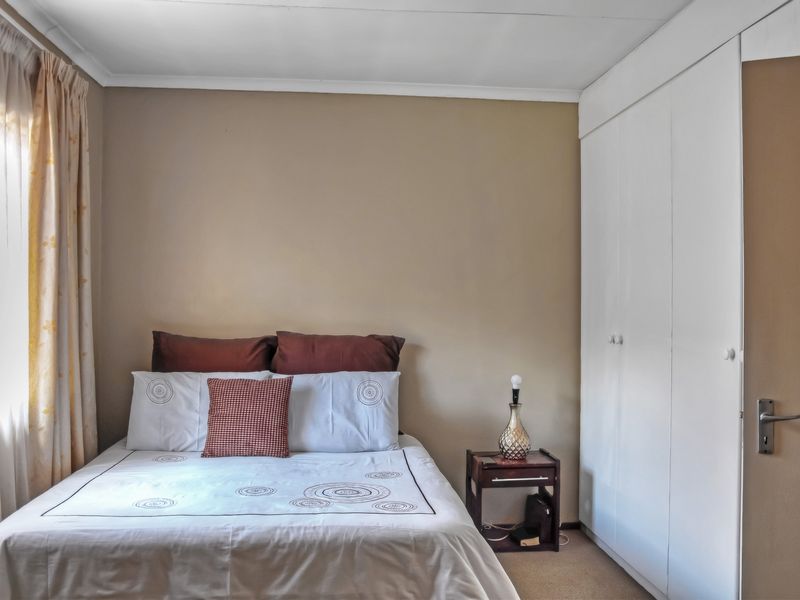 A functional bedroom featuring built-in cupboards and carpeted flooring, providing a neutral space ready for personalization.