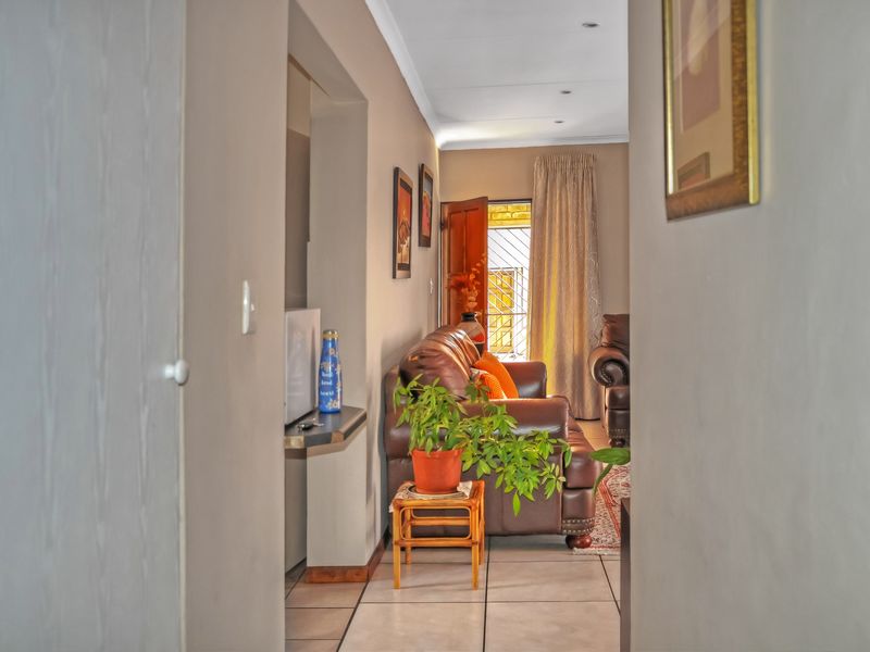 A view through a hallway into a living area featuring tiled floors, recessed lighting, and access to an outdoor space via a security gate.