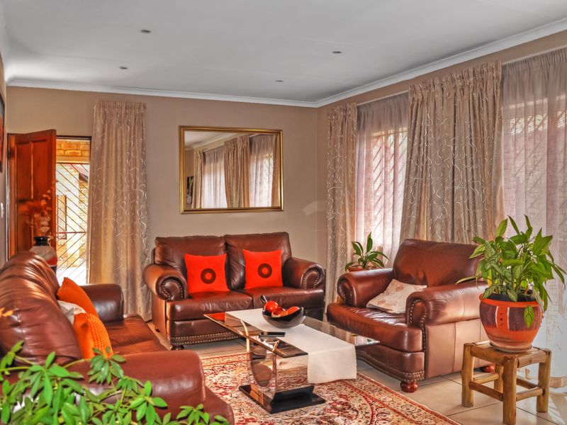A well-maintained living room featuring tiled flooring, recessed downlighting, and large windows with curtain tracks, providing a comfortable and functional space.