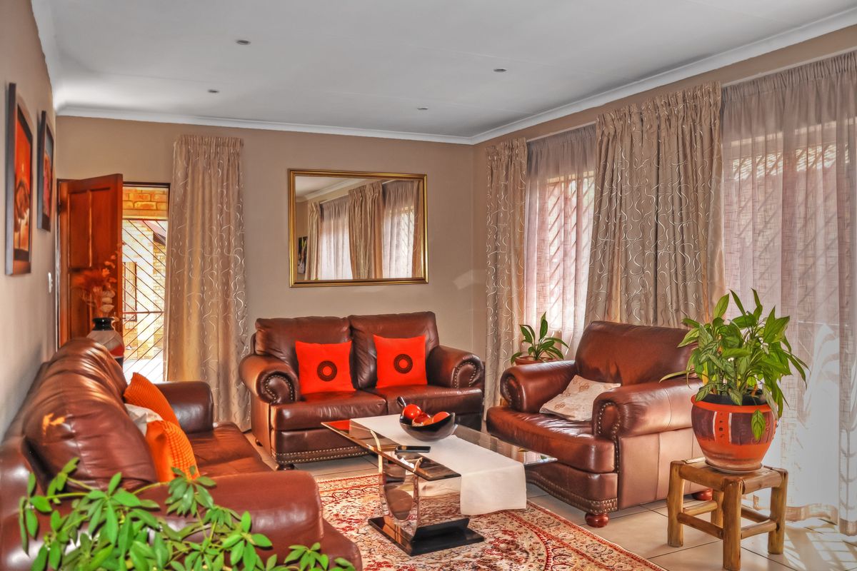 A well-maintained living room featuring tiled flooring, recessed downlighting, and large windows with curtain tracks, providing a comfortable and functional space.