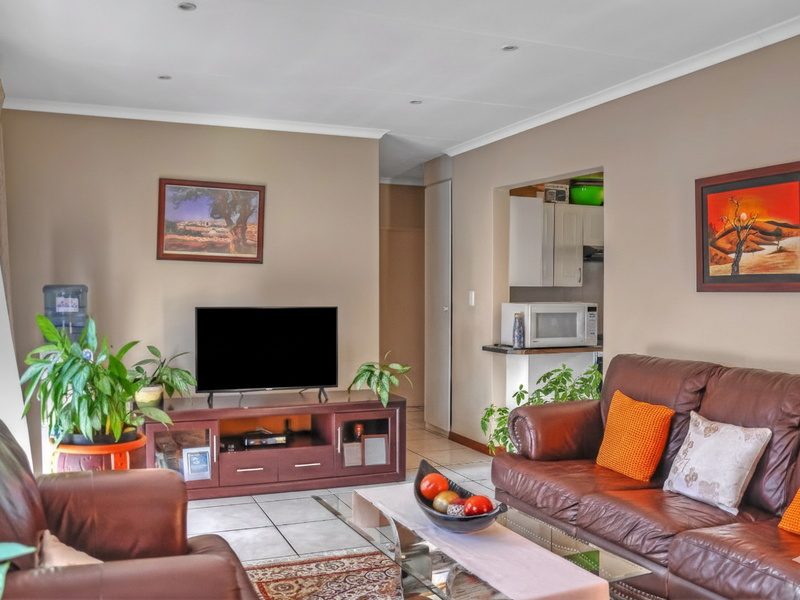 Open-plan living area featuring tiled flooring, recessed lighting, and a pass-through window connecting to the kitchen space.