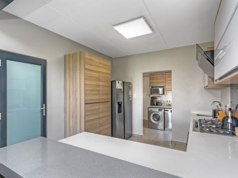 Modern open-plan kitchen featuring stone countertops, gas hob, extractor fan, and integrated cabinetry, with a convenient adjoining scullery area.
