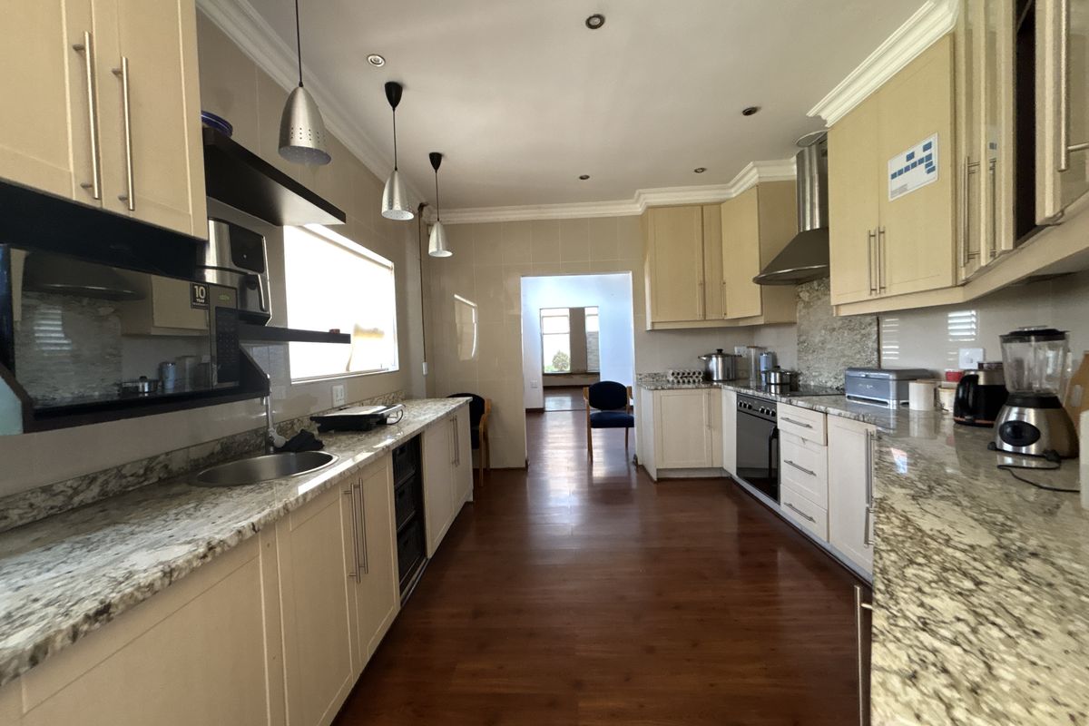 A well-appointed kitchen featuring granite countertops, ample built-in cabinetry, stainless steel appliances, and recessed lighting, with a seamless flow to the adjacent living area.