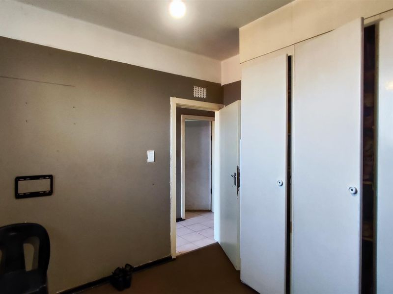 A bedroom featuring built-in cupboards and a neutral wall finish, offering a blank canvas for potential renovation or interior design updates.