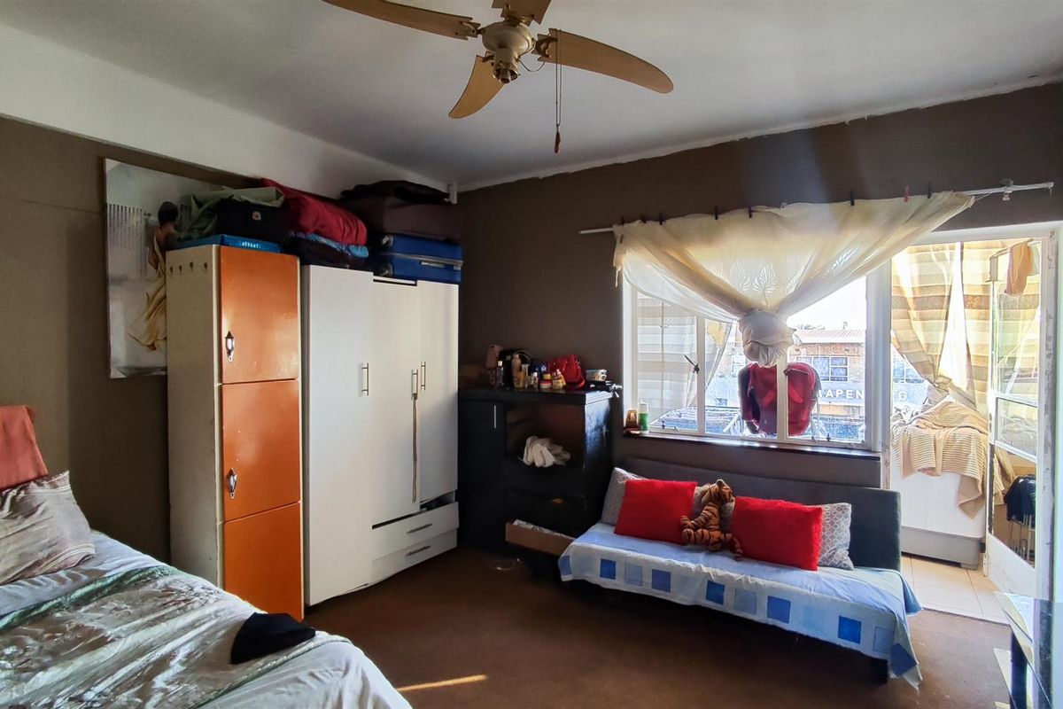 A bedroom featuring a ceiling fan, window, and direct access to an attached balcony.