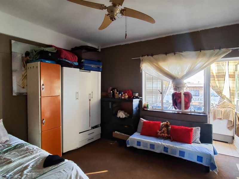A bedroom featuring a ceiling fan, window, and direct access to an attached balcony.