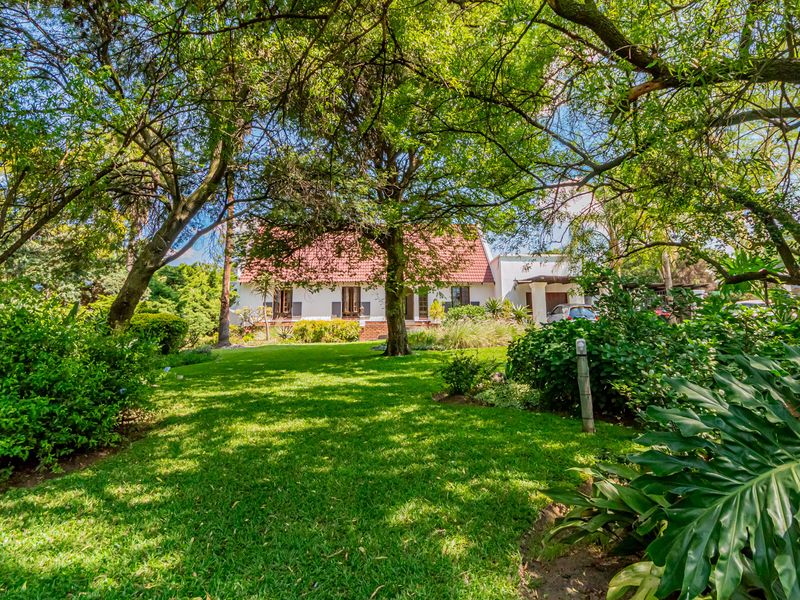 A lush, well-maintained garden featuring mature trees and a manicured lawn, providing a scenic view of the property's exterior facade.