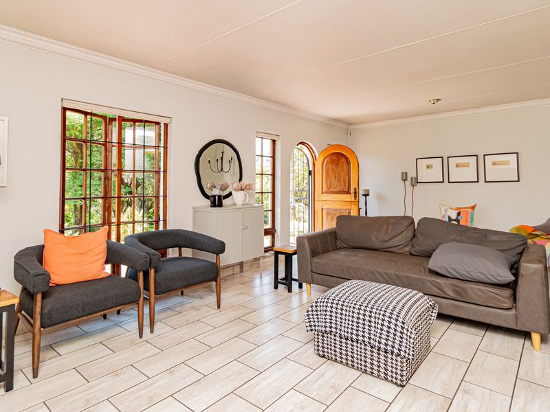 A bright and spacious living room featuring tiled flooring, coved ceilings, and natural light flowing through wooden framed sliding doors and an arched entrance.