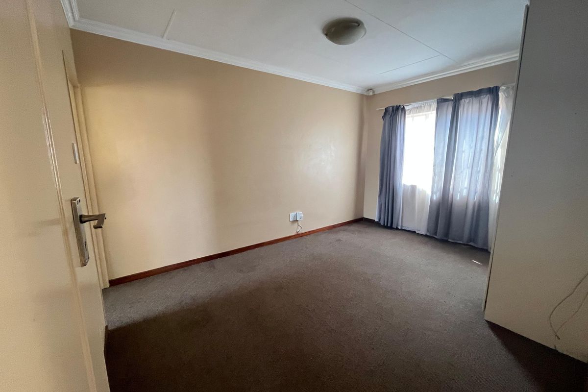 An empty bedroom featuring neutral wall paint, carpeted flooring, and a built-in cupboard, offering a blank canvas for personalization.