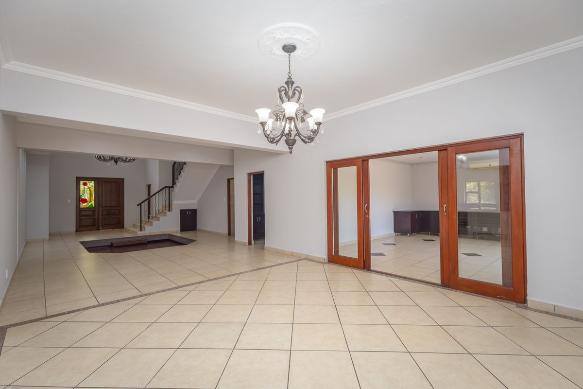 Spacious open-plan living area featuring ceramic tile flooring, a decorative chandelier, and sliding glass doors leading to an adjacent room.