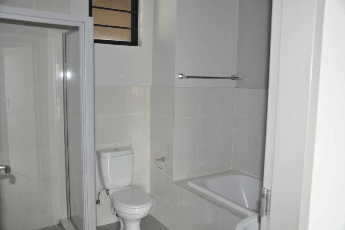 A functional bathroom featuring a white bathtub, a separate glass-enclosed shower, and a standard toilet with tiled walls.