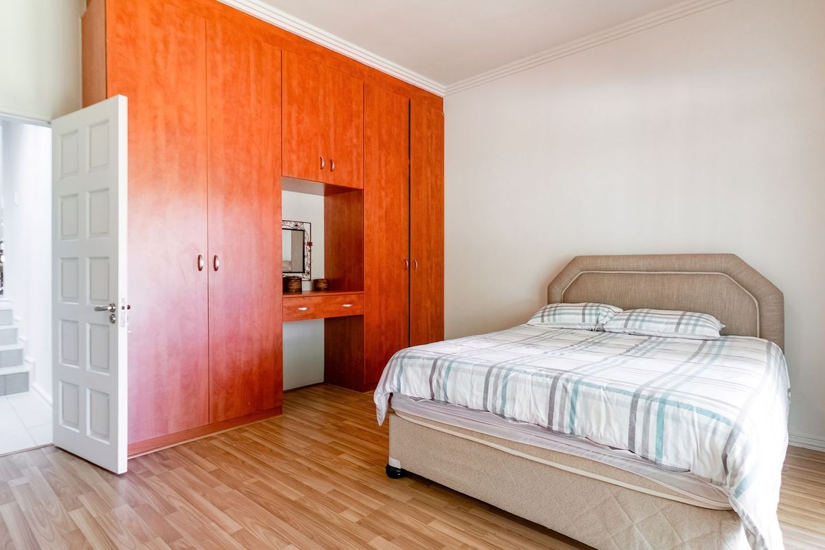 A bedroom featuring built-in wooden cabinetry with an integrated vanity and laminate flooring, offering a functional and well-maintained living space.