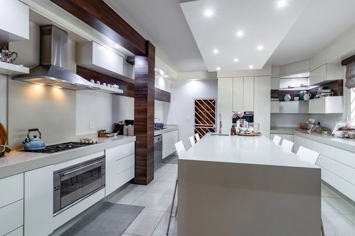 Modern, high-end kitchen featuring a large central island, sleek cabinetry, integrated stainless steel appliances, and recessed ceiling lighting.