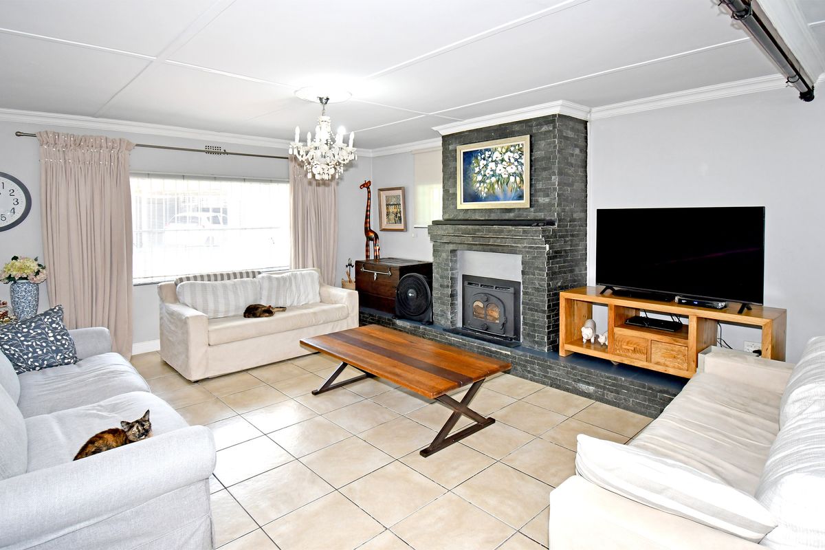 A comfortable living room featuring a prominent dark brick fireplace with a built-in wood-burning stove and tiled flooring throughout.