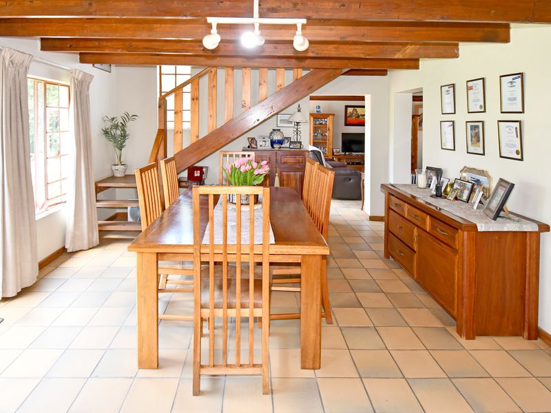 Dining area featuring exposed timber ceiling beams, a wooden staircase, and ceramic tile flooring, creating a warm and traditional atmosphere.