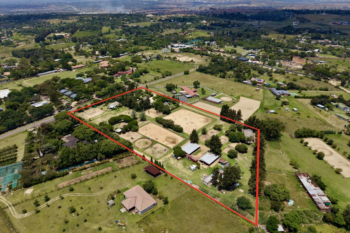 Aerial view of a large rural property featuring multiple equestrian paddocks, stables, and outbuildings within a clearly defined fenced perimeter.