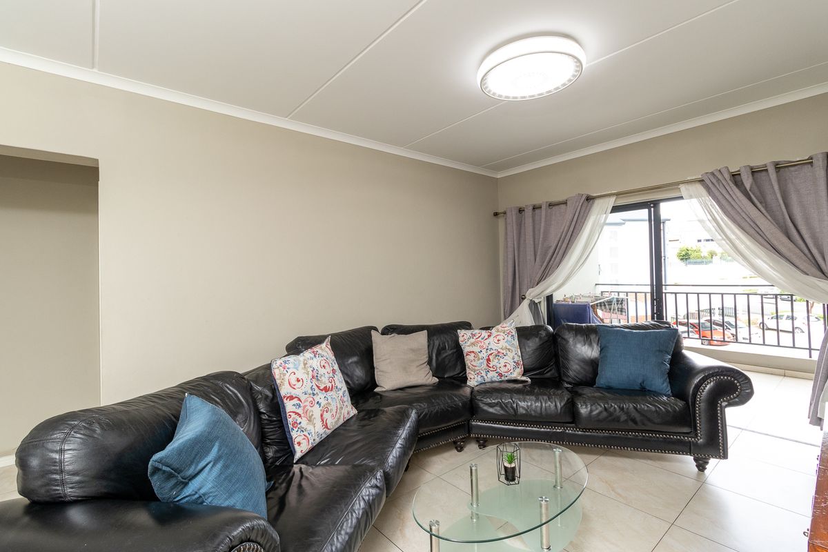 A well-lit living room featuring tiled flooring and direct access to a balcony through sliding glass doors.