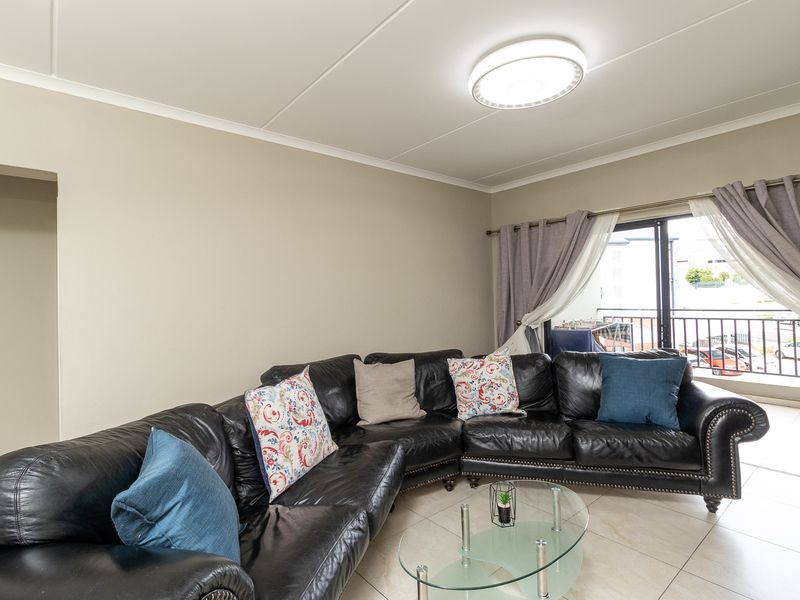 A well-lit living room featuring tiled flooring and direct access to a balcony through sliding glass doors.