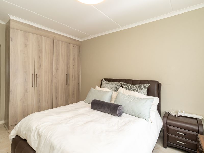 A well-maintained bedroom featuring neutral wall tones, tiled flooring, and ample built-in cupboard storage.