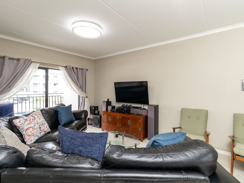 A spacious living room featuring tiled flooring, a ceiling light fixture, and a sliding glass door providing access to an outdoor balcony area.