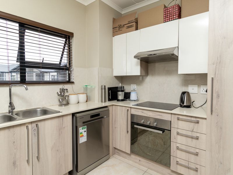 Modern kitchen featuring light wood-grain cabinetry, stone countertops, integrated stainless steel appliances, and a functional layout with ample storage and natural light.