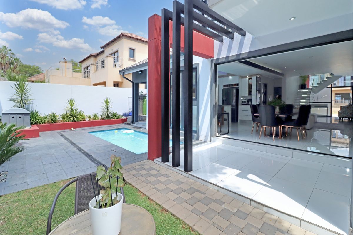 Rear exterior view featuring a swimming pool, paved patio area, and seamless indoor-outdoor flow through large sliding glass doors.
