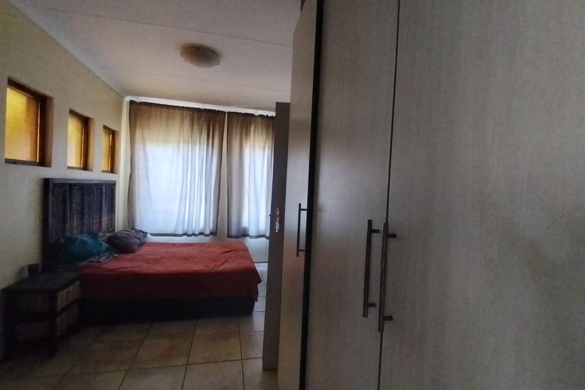 A bedroom featuring tiled flooring, built-in cupboards, and multiple recessed windows, providing a functional space with natural light.