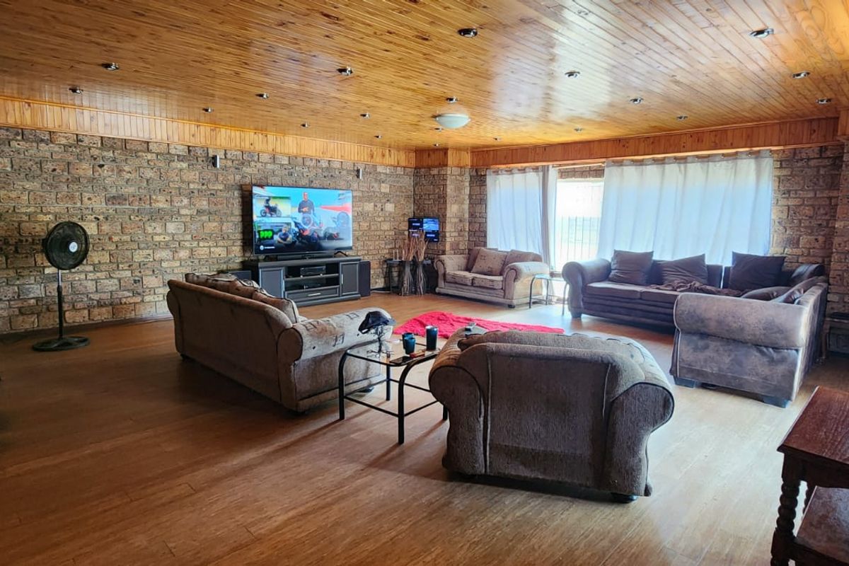 Spacious living room featuring exposed brick walls, a polished timber-clad ceiling with recessed lighting, and large windows allowing for natural light.