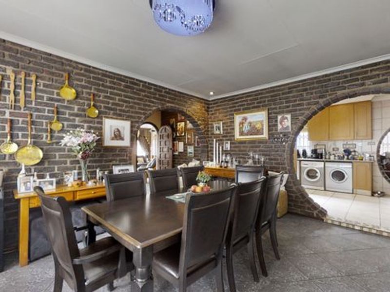Open plan dining area featuring exposed brick walls and distinctive arched architectural openings leading into a functional kitchen space.