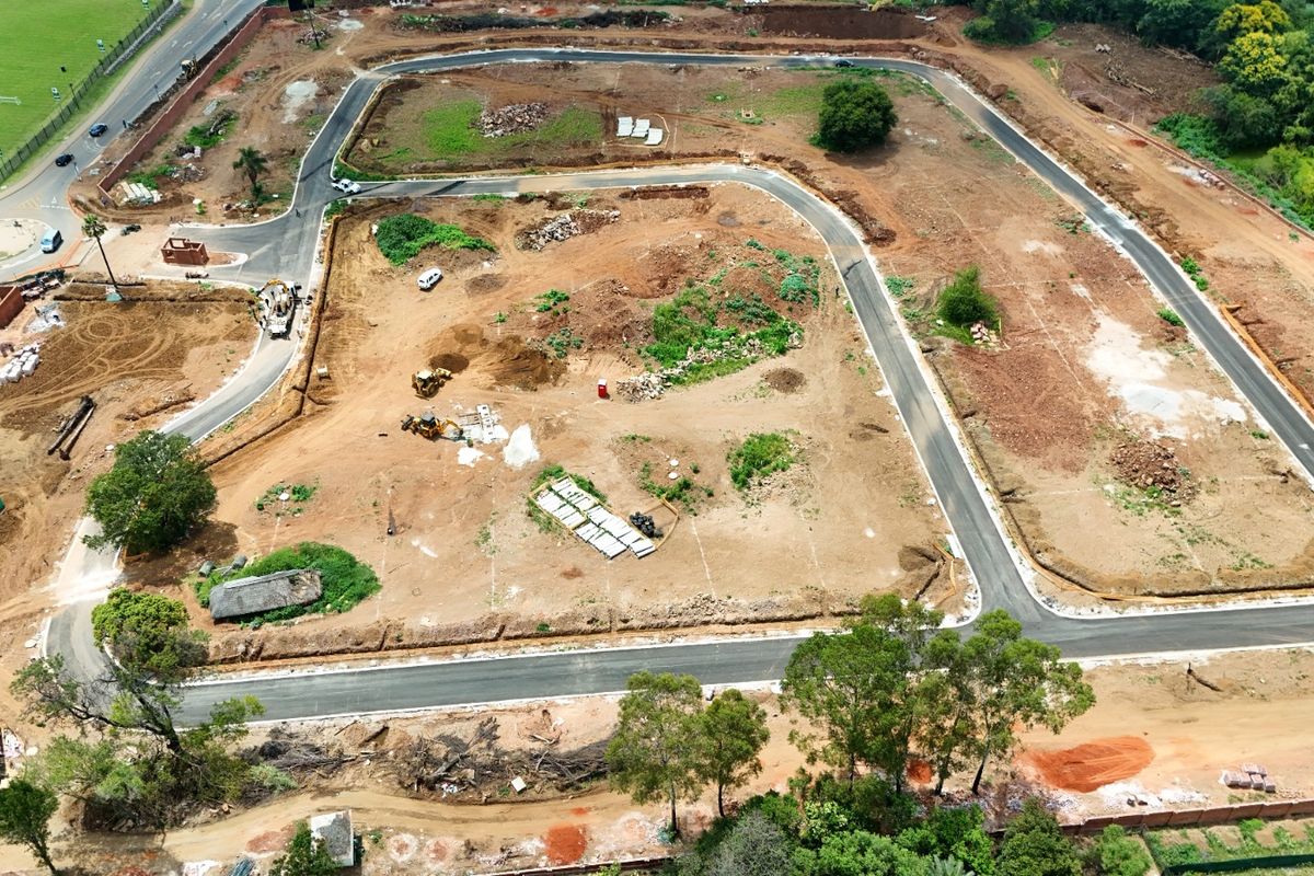 Aerial view of a residential development site showing established paved roads, cleared plots, and ongoing infrastructure preparation.